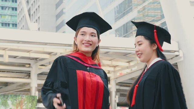 Young asian women in graduation gown outfit meeting outdoor and take a selfie together with smile and happiness in university graduated event