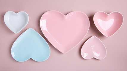 Heart shaped blue, pink and white empty plates on pink background. Happy Valentine's Day.