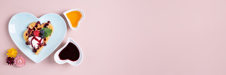 Heart shaped  belgian waffles with Ice-cream and berries on pink background. Tasty breakfast. Happy Valentine's Day. Top view, banner.