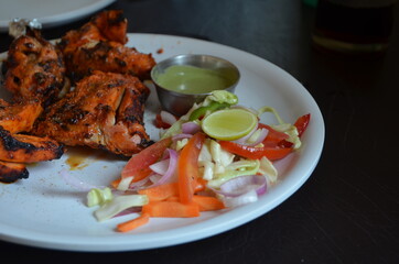 Indian food. Red chicken in tandoor with fresh vegetables vegetables and delicious naan with cheese