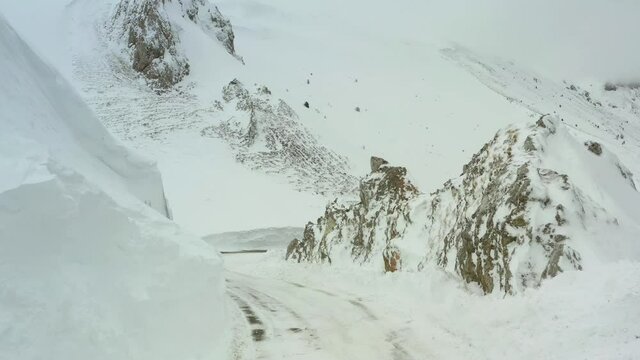 Strda di montagna innevata, in mezzo agli alberi coperti di neve.
Vista aerea di paesaggio invernale. Strada di montaggna sotto la neve in mezzo al bosco di pini