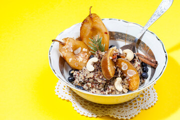 
Sweet quinoa porridge with pear and berries in coconut milk. Healthy breakfast. Top view, flat layer bright yellow background