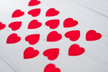 Small red hearts made of paper evenly lined on a white old wooden background .Concept of texture, valentines day.