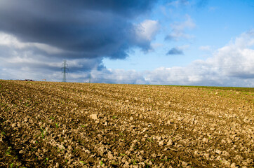 Agricultural field in the stormy weather with plowed soil prepared for sowing