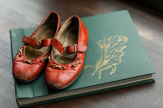 old vintage green photo album with red worn children's shoes.Nostalgic Old Family Photo Albums