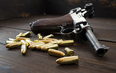 Historic Luger P08 Parabellum handgun, old soviet TT handgun and shiny 9 mm bullets on wooden...