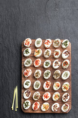 Soft cheese topped with vegetable and spices on wooden table on black stone background
