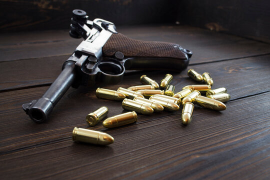 Historic Luger P08 Parabellum handgun, old soviet TT handgun and shiny 9 mm bullets on wooden vintage background