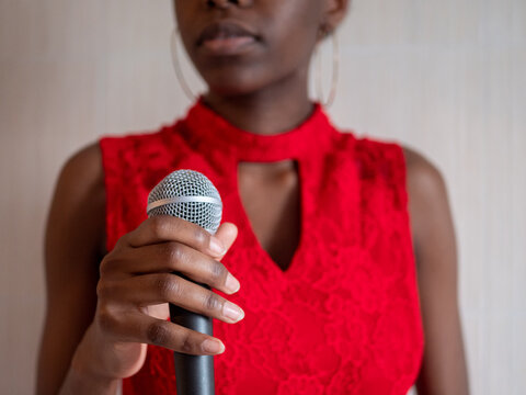 African american woman in red dress singing karaoke with microphone hand close-up shallow depth of field
