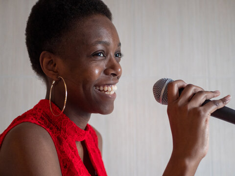 African american woman in red dress singing karaoke with microphone hand close-up shallow depth of field