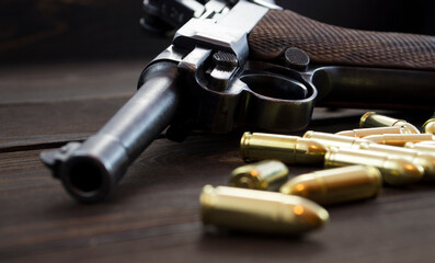 Historic Luger P08 Parabellum handgun, old soviet TT handgun and shiny 9 mm bullets on wooden vintage background