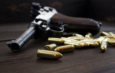 Historic Luger P08 Parabellum handgun, old soviet TT handgun and shiny 9 mm bullets on wooden vintage background