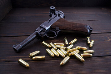 Historic Luger P08 Parabellum handgun, old soviet TT handgun and shiny 9 mm bullets on wooden vintage background