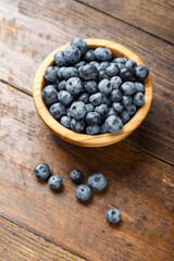 Freshly picked blueberries in wooden bowl on wooden background.  Concept of healthy and dieting eating.