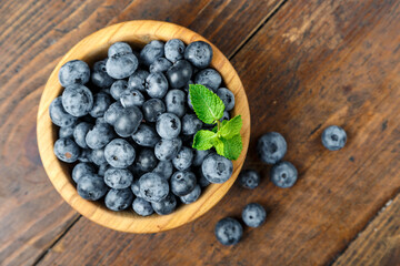 Freshly picked blueberries in wooden bowl on wooden background.  Concept of healthy and dieting eating.