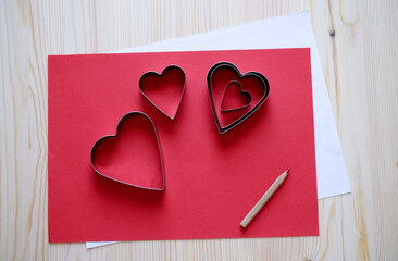 Red and white paper with hearts forms for valentine's handmade greeting card at the wooden table background