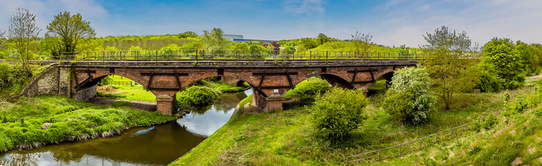 Fototapeta na wymiar A panorama view of along Chesterfield canal towards the Manton railway viaduct and the town of Worksop in Nottinghamshire, UK in springtime
