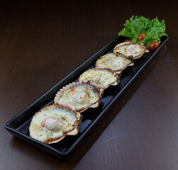 Baked scallops with cheese in black plate