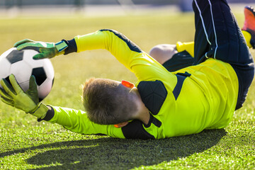 Soccer Goalie Catching Ball. Young Boy Goalkkeeper Saving Goal. Acrobatic Football Goalkeeper Save. Soccer Player in a Goal on a Sunny Summer Day. Soccer Goalie Training Unit
