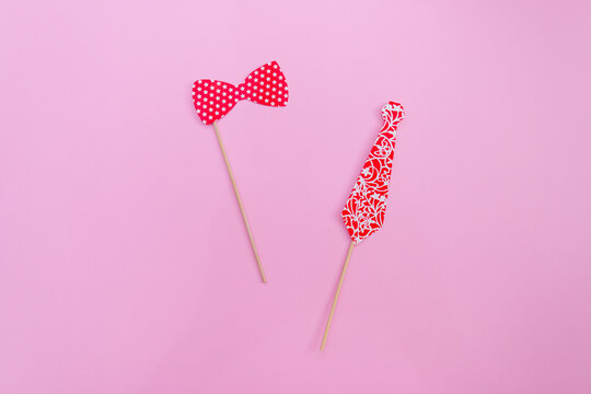 flatlay false paper photo stand props: bow tie and classic tie on pink background copyspace for Valentine's day greeting card