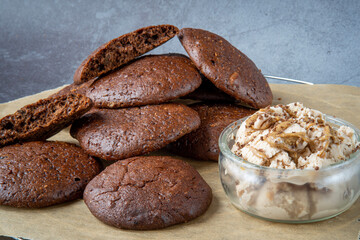 Pile of fluffy chocolate brownie cookies with a broken cookie on top served with peanut butter ice...