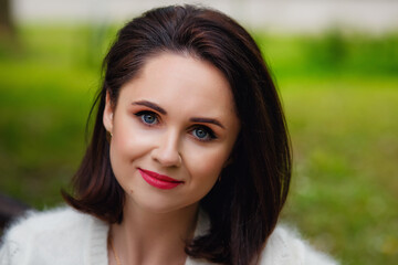 Fototapeta premium Portrait of a beautiful young lady sitting on a bench in a spring Park.