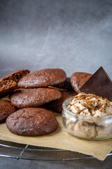 Pile of fluffy chocolate brownie cookies served with peanut butter ice cream and dark chocolate. Healthy homemade gluten free chocolate chip cookies on a cooling rack.
