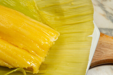 Pamonha - comida típica brasileira; Uma pamonha com a palha do milho, dentro de um prato branco.