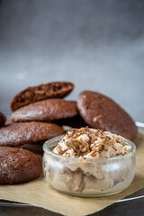 Peanut butter ice cream in a glass jar and a pile of fluffy chocolate brownie cookies with a broken cookie on top. Healthy homemade gluten free chocolate chip cookies on a cooling rack.