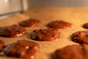 Selective focus on unbaked chocolate cookie dough on a baking tray inside the oven. Pre-baked healthy gluten free brownie cookies with chocolate chips.
