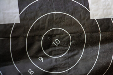 Shot up target with bulls-eye and with the traces of an accurate hit in the center