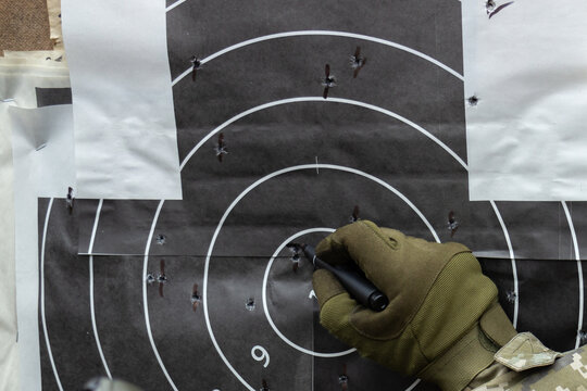 Shot up target with bulls-eye, holes from bullets, the instructor marks the shooter's hit