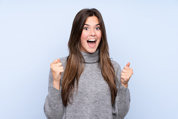 Teenager Brazilian girl over isolated blue background celebrating a victory in winner position