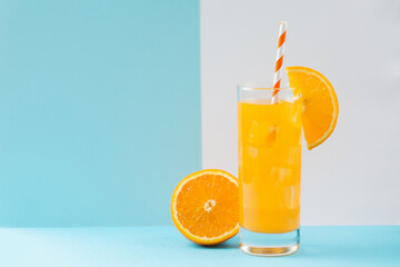 Cold orange juice drink in glass and fresh citrus on pastel blue and white background. Healthy drink.