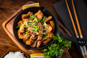 Teriyaki chicken breast in frying pan with rice and sesame seeds top view, traditional asian food