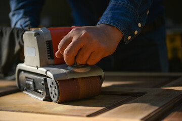 The carpenter is sanding the wood,The carpenter is smoothing the wood to remove the burr.