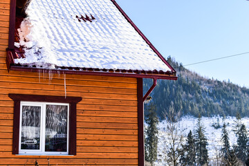 Winter landscape, icicles on the roof of the house