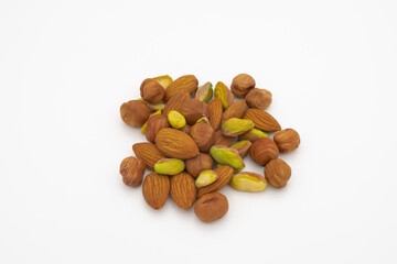 pile of pistachios almonds and hazelnuts, hazelnuts isolated on white background