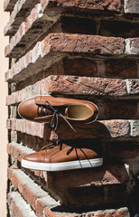Fototapeta na wymiar Brown sneakers or shoes with white sole, close up. Bricks background