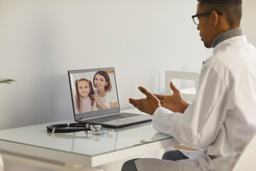 Obraz premium Doctor video calling patients. Family practitioner or pediatrician sitting at laptop computer and talking to mother and daughter. Telemedicine, eHealth service and virtual medical consultation concept