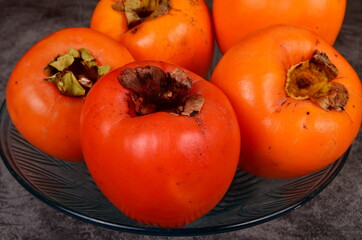 Group of Ripe orange persimmon fruit.Persimmon fruits in plate, rustic background, Hurma fruit