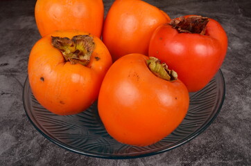 Group of Ripe orange persimmon fruit.Persimmon fruits in plate, rustic background, Hurma fruit