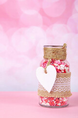 jar with colorful hearts on a pink background with bokeh