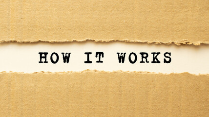 Text HOW IT WORKS appearing behind torn brown paper. Top view.