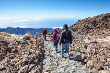 Group of hikers walking on pathway in mountains, stone hike route to the Teide volcano. Tenerife island, Canary, Spain