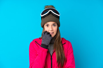 Teenager skier girl with snowboarding glasses over isolated blue background nervous and scared