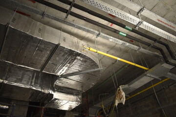 MEP works in civil construction site. Aluminum fabricated air flow duct and steel tray supporting works. ducting work. duct Insulation. HVAC system in the construction site.