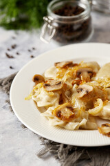 Christmas dumplings stuffed with mushrooms and cabbage on a white plate on a rustic wooden table. A traditional dish on Christmas Eve in Poland. Dumplings, dumplings, pies, pies - stuffed dumplings.