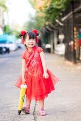 Portrait of happy Asian little child wearing Chinese traditional dress laughing and smiling. Adorable girl with a yellow umbrella. Chinese new year. Traditional Asian new year. Happy face.