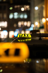 Vertical shot of the yellow TAXI signs on the taxis captured at night
